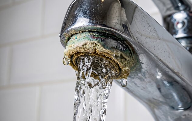 kalkablagerungen-und-korrosion-an-einem-wasserhahn-aus-dem-wasser-fliesst